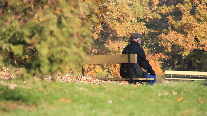 Older man rests on the bench in autumn park