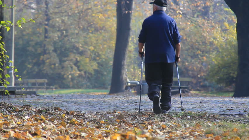 Older man walks through park and exercise