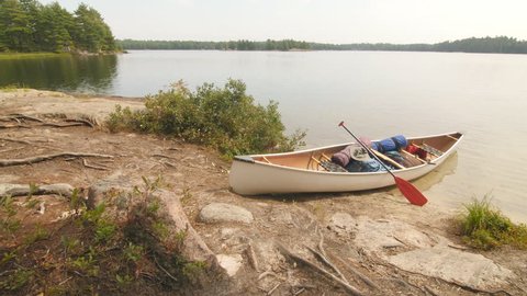 Canoe with paddle and camping equipment including backpacks on island beach. Massassauga Provincial Park, Ontario, Canada.
