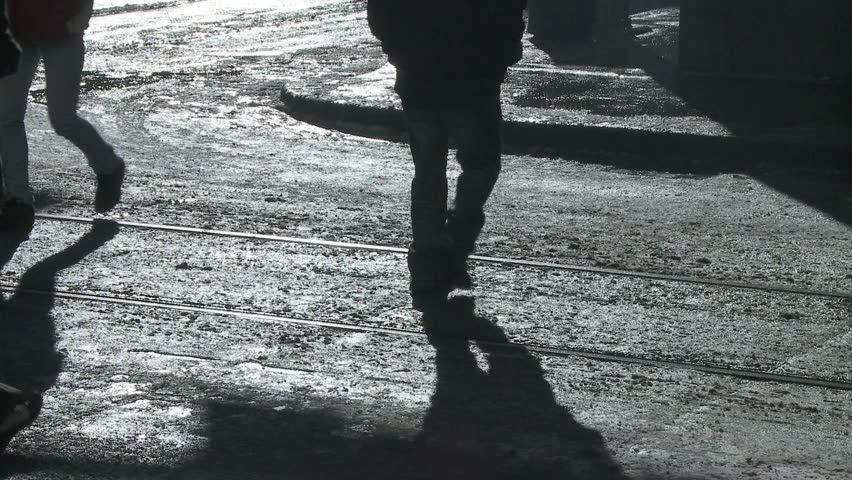 Pedestrian shadows on a slushy crosswalk