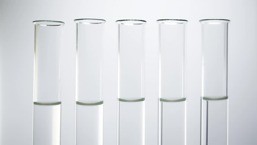 На столе стоят три склянки с водой. Пробирка с раствором. Прозрачный раствор. Пробирка с жидкостью. Прозрачный раствор в пробирке.