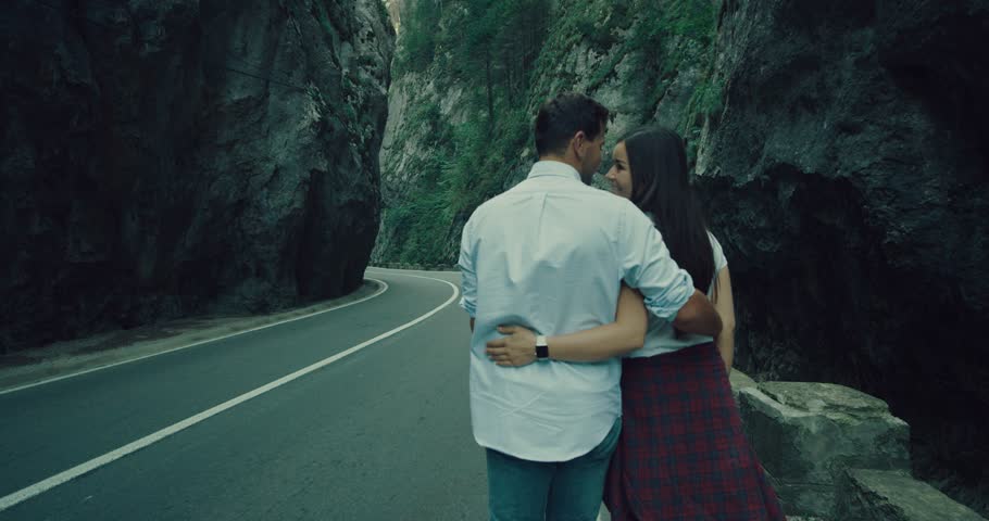 a  lovely couple in  walking on the road huging and smile