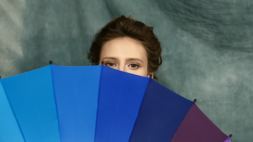 Smiling young brunette woman in white blouse with multi-coloured umbrella