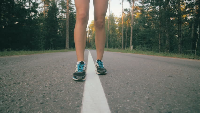 Athletic youg woman Jogging in a park. Close up of running shoes and legs in action. Stedycam shot.