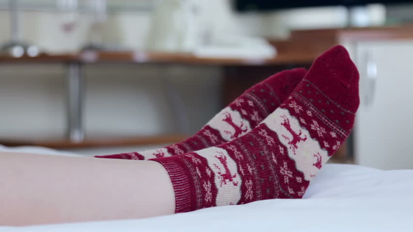 Female legs in Christmas socks in bed. dolly shot