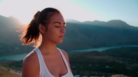 4K beautiful girl in white clothes doing yoga in the mountains,sunrise,sun glare, close-up