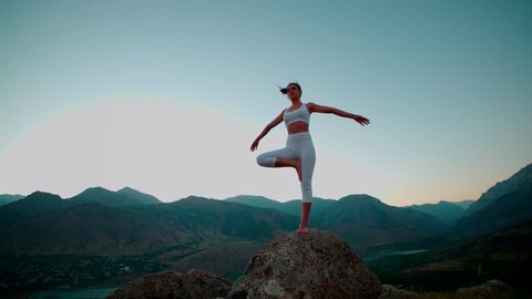4K beautiful girl in white clothes doing yoga on the beautiful backdrop of the mountains,slow motion