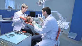 Little girl undergoing dental procedure carried out by dentist and his helpful assistant