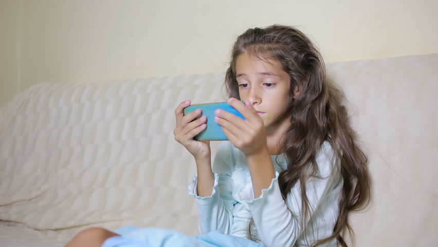 Girl child with a cell phone browses the Internet