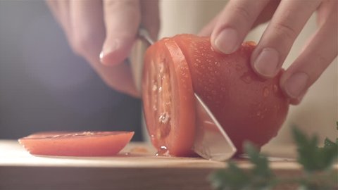 Female hands cutting tomato
