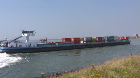 SEAPORT ROTTERDAM -  JULY 2016: Container ship passing the Rozenburg peninsula at Breeddiep, an important connection for inland shipping. Crane vessel in background.