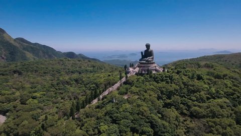 Aerial drone flight towards the peaceful Tian Tan bronze Buddha statue, part of the Po Lin monastery in Hong Kong, located in a beautiful mountain setting. 스톡 비디오