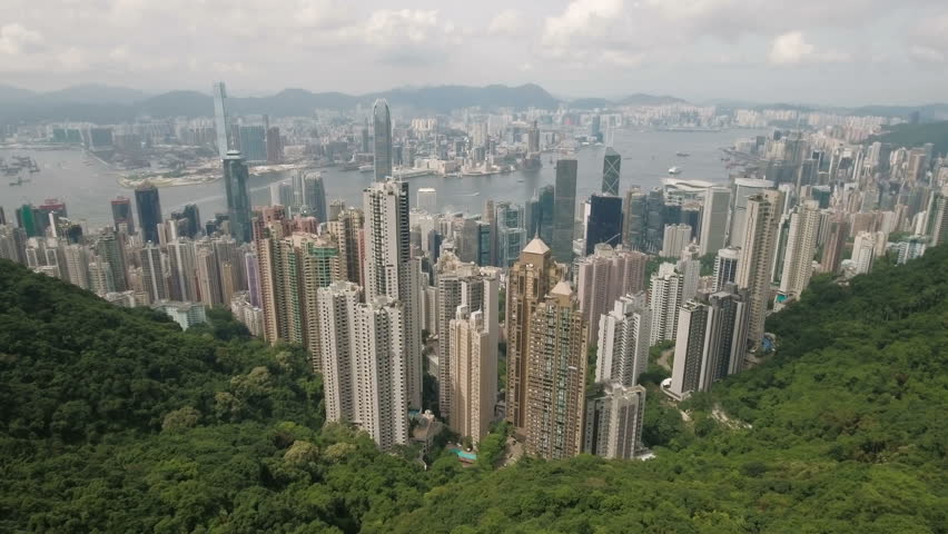 HONG KONG - JULY 2016: Aerial drone view of the beautiful high-rise commercial and residential buildings of Hong Kong island and Kowloon. Flying from the Victoria Peak towards the skyline of the city.