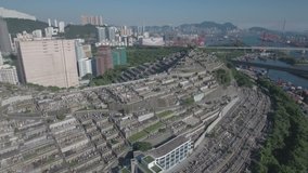 Sideways aerial shot of a peaceful cemetery in Hong Kong, with the city's skyline in the background. 