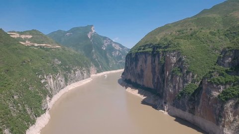 High angle aerial drone view of a cruise ship sailing through the beautiful massive cliffs of the Qutang Gorge along a famous stretch of the Yangtze river in central China
