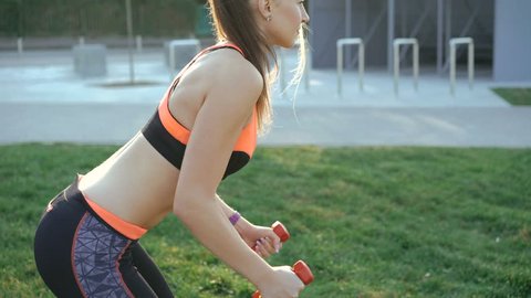 Young girl doing morning exercises with weights outdoor in 4K