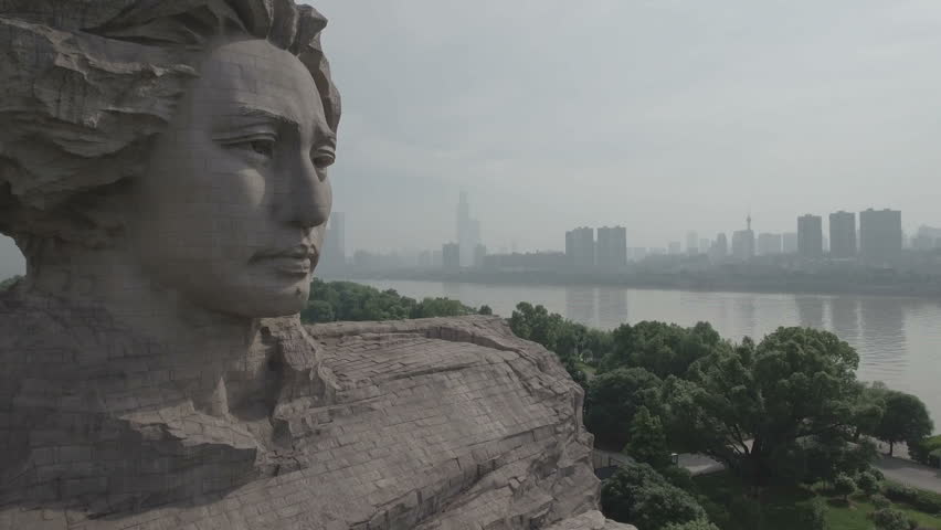Tilting rising aerial shot of a statue of a young Mao Zedong in Changsha, a city where he attended school. D-log profile on DJI Phantom.