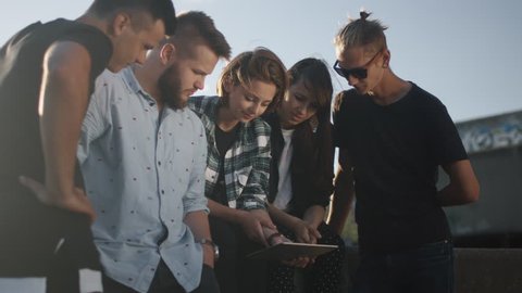 Group of Teenagers Using Tablet Computer for Entertainment Outdoors in Urban Environment Shot on RED Cinema Camera in 4K (UHD).