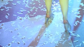 Close up of female legs wearing high heels shoes cheerfully dancing at night club. Top view video of anonymous dancer dancing in beautiful changing colorful disco lights. Real time full hd footage.