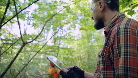 Forestry worker holding a tablet in woodland