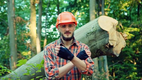 Young lumberjack in front of cut trunks in forest