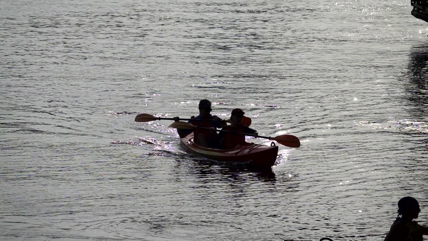 Couple silhouette rowing a kayak, slow motion