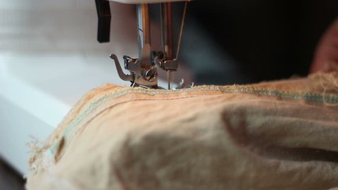 Close up shot of sewing machine sewing a light brown fabric