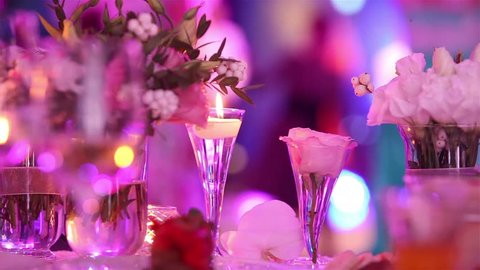 candles at the wedding table, blurred silhouettes of people dancing in a disco, banquet, decoration, restaurant, close-up