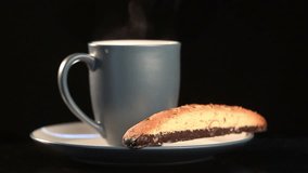 HD video of a steaming cup of coffee and a biscotti cookie