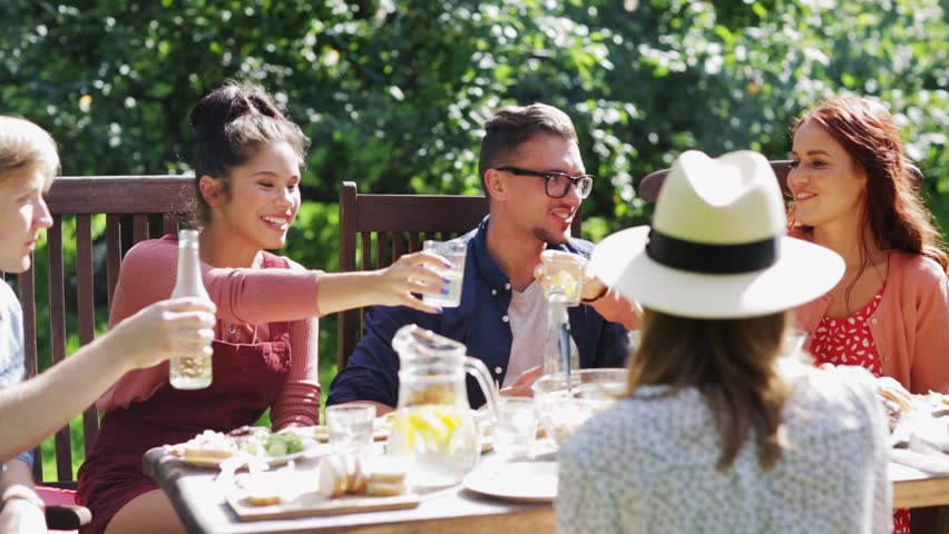 Leisure, holidays, eating, people and celebration concept - happy friends having dinner and clinking drinks at summer garden party | Shutterstock HD Video #19884250