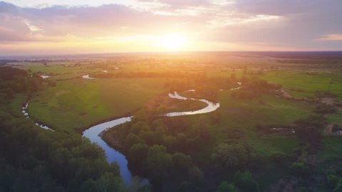 Aerial View: Flight over the Beautiful River and Green Wood. Sunset soft light with pastel cloudy sky. Magestic landscape. 4K resolution.