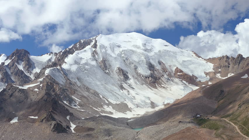 Time Lapse of snow ice peak at sunrise. There are houses at the foot of the mountain for a scale.
