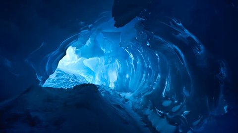 Blue ice cave covered with snow and flooded with light. Slow motion 4K footage