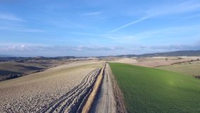 drone take off over the road aerial shot, gorgeous tuscany hills landscape, flying above the plowed fields, tuscany flyover