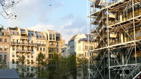 Paris, France: Left end of the Centre Pompidou (national modern art museum) and nearby apartments, with pigeons flying and all bathed in warm early evening sunlight. 