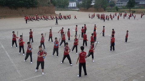 SHAOLIN, CHINA - MAY 2016: Shaolin kung fu students practice with swords at the grounds of the Shaolin temple
