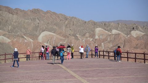 ZHANGYE, CHINA - MAY 2016: Tourists visit a platform to admire the 'rainbow mountains' of Danxia national park in China
