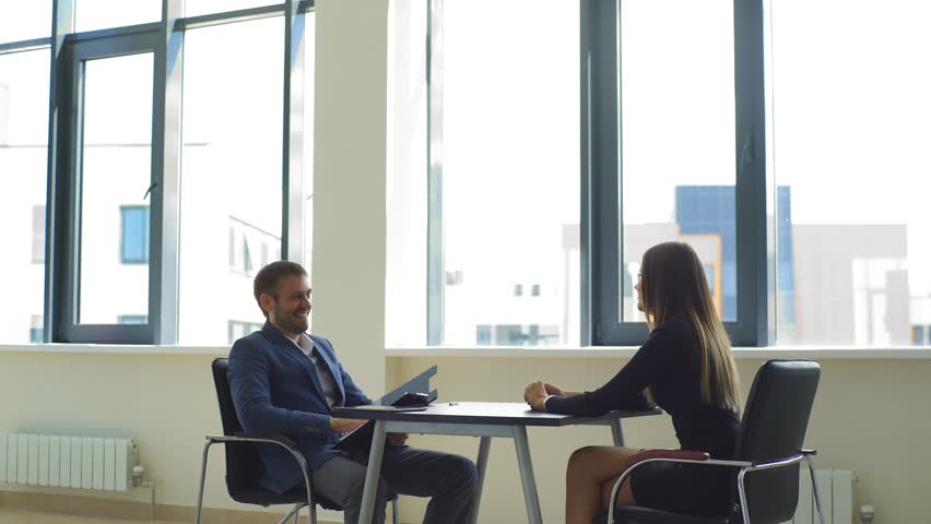 smiling the employer asks questions to the woman in the interview