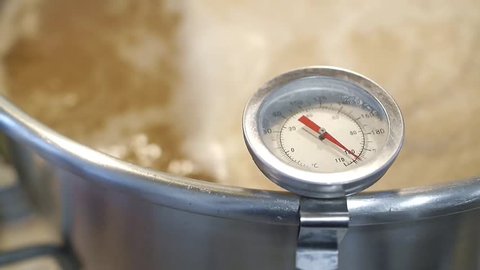 Stainless steel kitchen thermometer measures the temperature of boiling wort beer homebrew ( warm tone color ) 