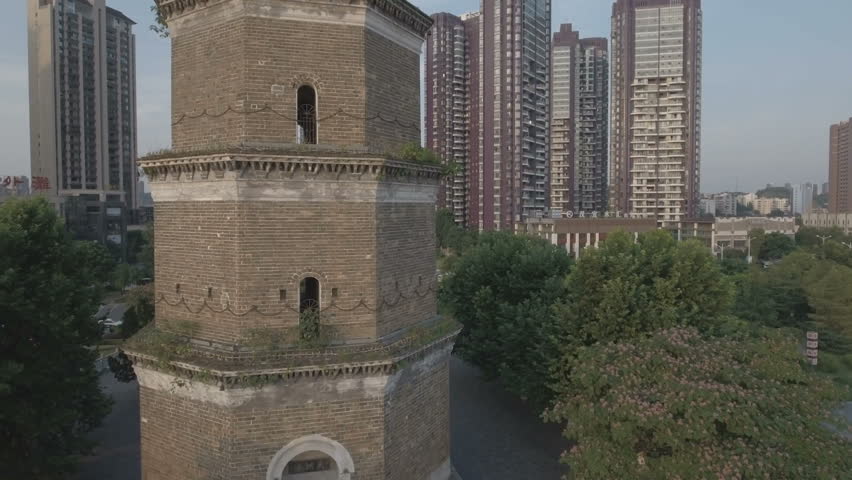 Rise up drone shot of a historic Chinese pagoda with modern flats in the background. 