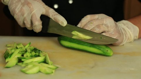 Close up of the hands of a chef chopping cucumber