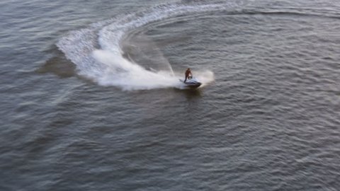 Hi speed adrenaline ride on the water scooter in the sunset, aerial shot
