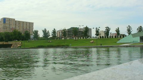 Lake and green grass in the middle of city. Cars crossing. Baku Azerbaijan.