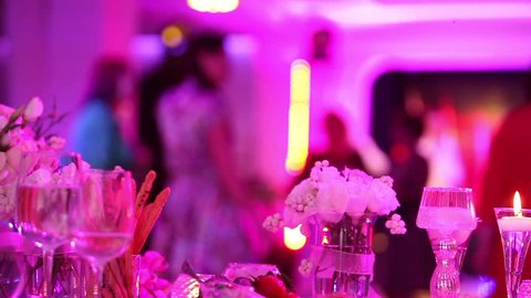 decorative candles at the wedding table, blurred silhouettes of people dancing in a disco, edding table  decoration on background