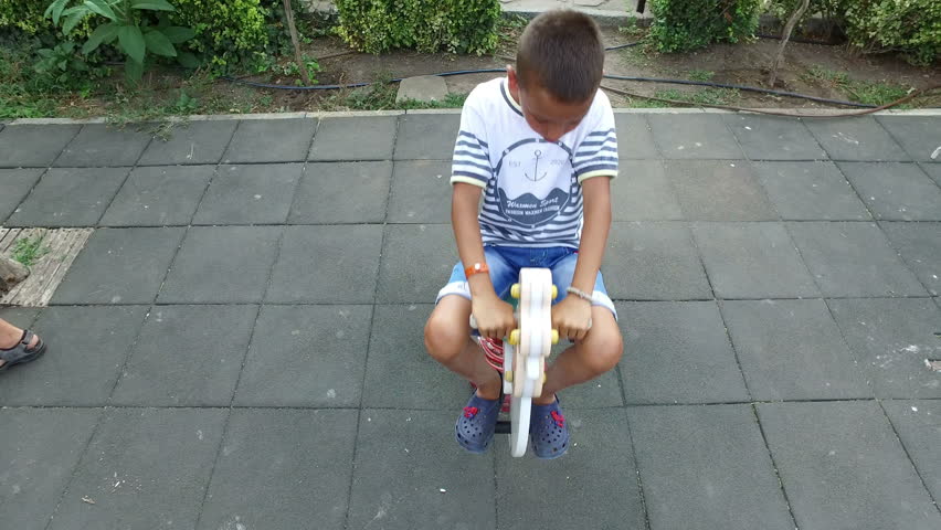Boy is swinging on spring toy horse at playground