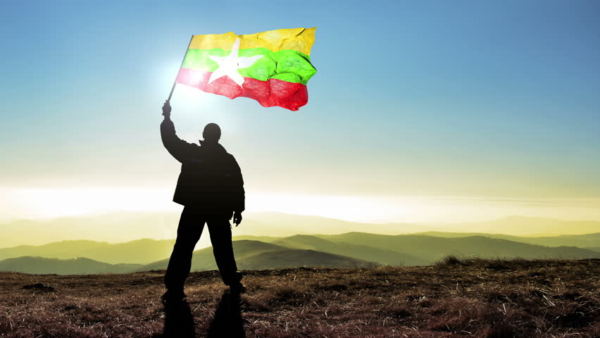 Successful silhouette man winner waving Myanmar flag on top of the mountain peak, 4k cinemagraph
