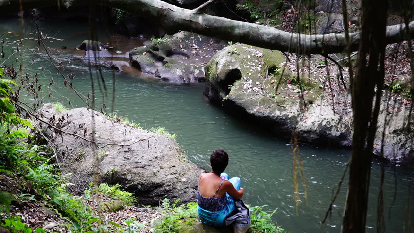 Female on bank of jungle river.