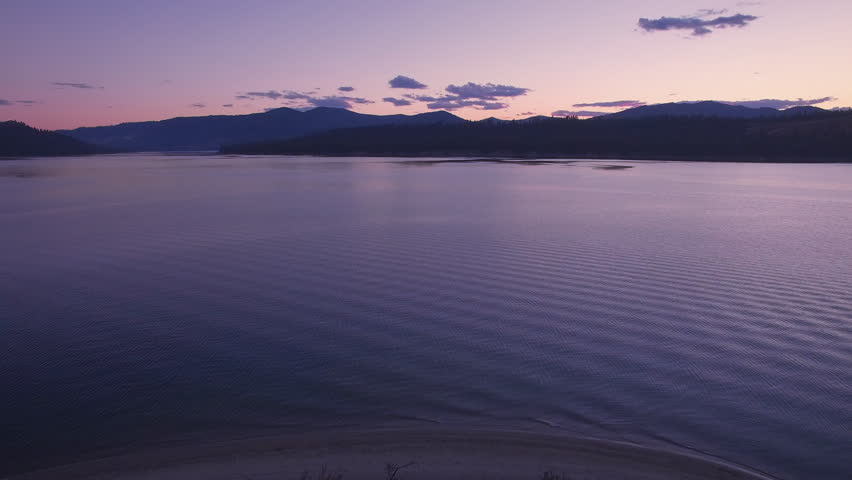 Drone Flying Over Calm Lake Water After Sunset with Vibrant Pink and Purple