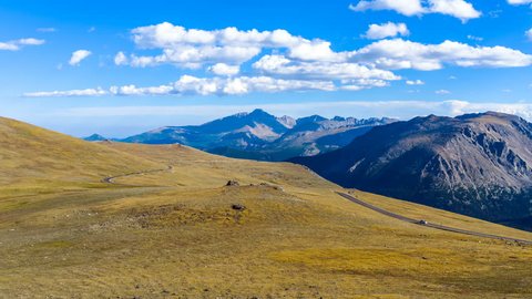 Trail Ridge Road - Time-lapse of a panoramic evening view of busy Trail Ridge Road winding through vast alpine tundra at top of Rocky Mountains, with Longs Peak (14,255 ft) rising high in background.