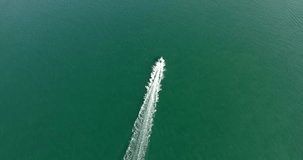 Aerial footage top view with motor boat at high speed cuts the waves while is leaving a long white trail. Conceptual video presentation for tourism. Expensive lifestyle and kind of leisure